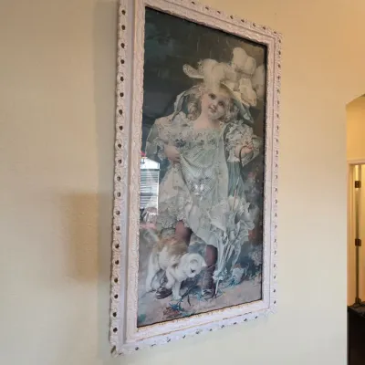 Vintage framed print depicting a young Victorian girl with a cat, housed in an ornate white-painted wooden frame.