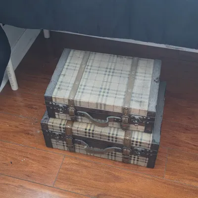 Pair of decorative plaid suitcases with faux-leather straps and metal hardware, stacked on a wood floor.