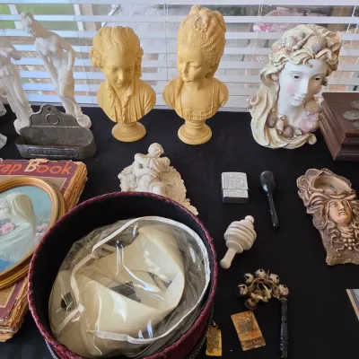 Assortment of vintage collectibles including classical-style bust sculptures, a vintage scrapbook, a round hat box with a white hat, and...
