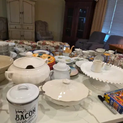 Assorted vintage kitchenware and tableware, featuring a white enamel bacon grease canister, ceramic soup tureen, milk glass cake stand,...