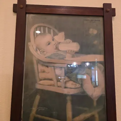 Vintage Lilybrand Dairy advertisement print featuring an illustration of a baby in a high chair, housed in a dark wood Mission-style frame.