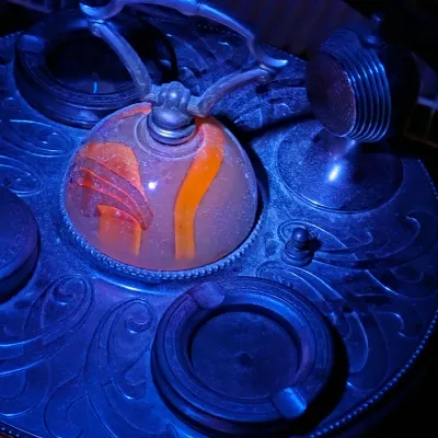 Vintage Art Deco smoking stand tray featuring integrated ashtrays, a lighter, and a central orange slag glass element glowing under UV...