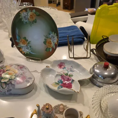 Assortment of vintage porcelain and glass tableware, including a hand-painted floral plate on a stand, a leaf-shaped divided dish, a...