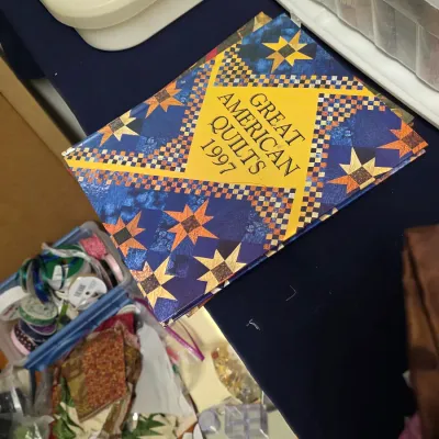"Great American Quilts 1997" hardcover book, featuring a colorful quilt-patterned cover design, surrounded by various sewing...