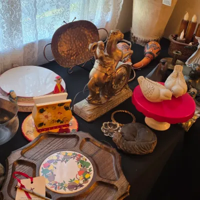 Assortment of vintage home decor items, including a wooden serving tray with a ceramic center, a gold-tone horse and rider clock, ceramic...
