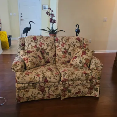 Traditional floral print loveseat with matching throw pillows and a pleated skirt, shown in good condition.