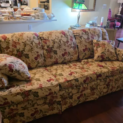 Traditional three-cushion sofa featuring a classic floral chintz upholstery in shades of burgundy, cream, and green, complete with...