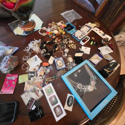 Assortment of vintage and contemporary costume jewelry, including beaded necklaces, brooches, rings, and boxed sets, displayed on a...