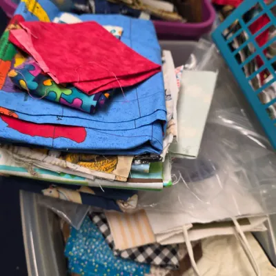 Assorted fabric remnants and quilting squares in various colors and patterns, stored in plastic bins.