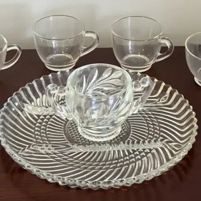 Vintage clear glass punch or snack set featuring a ribbed serving platter, a double-handled center cup with leaf patterns, and six...