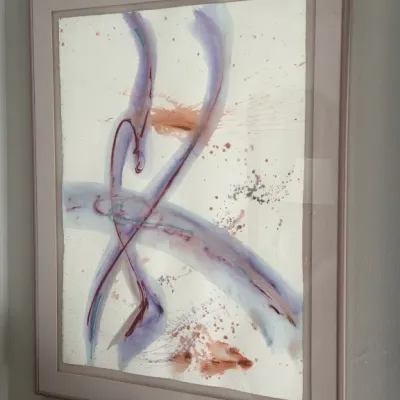 Sale Photo Thumbnail #107: Framed abstract watercolor painting featuring fluid purple, pink, and blue brushstrokes with splattered accents, presented in a light pink frame with a matching mat.