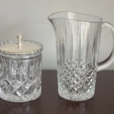 Vintage cut glass pitcher and matching lidded biscuit jar with a silver-toned metal lid, featuring a classic diamond and vertical wedge...