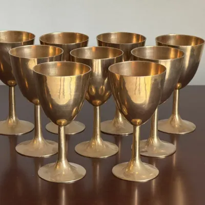 Set of eight vintage brass goblets, showing a warm patina and classic mid-century design.