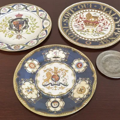 Three vintage British royal commemorative porcelain plates featuring heraldic crests and the Order of the Garter motto, accompanied by a...