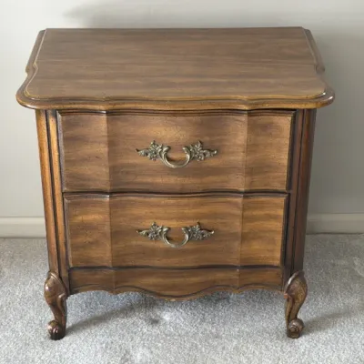 Sale Photo Thumbnail #104: French Provincial style two-drawer nightstand with a shaped top, serpentine drawer fronts, ornate brass pulls, and cabriole legs.