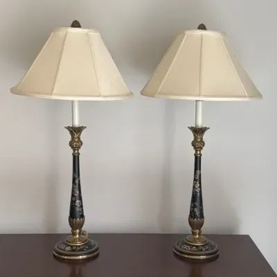 Pair of vintage Stiffel-style table lamps featuring black columns with silver floral details, brass accents, and cream-colored fabric...
