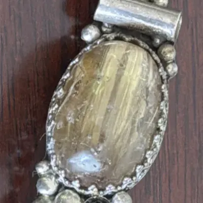 Sale Photo Thumbnail #288: Vintage sterling silver pendant featuring a large oval rutilated quartz cabochon, accented with a small black onyx stone and decorative silver beadwork.