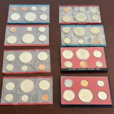 Sale Photo Thumbnail #304: Collection of United States proof and uncirculated coin sets, including Eisenhower dollars and Bicentennial coinage in original plastic packaging and display cases.