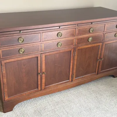 Traditional mahogany buffet cabinet featuring four lower doors, eight drawers with decorative brass ring pulls, and a pull-out laminate...