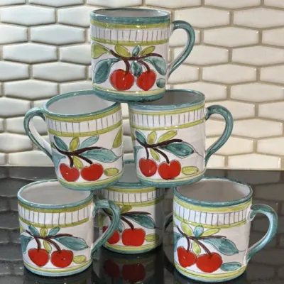 Set of six hand-painted Italian ceramic mugs featuring a cherry motif with green and yellow accents, stacked in a pyramid.