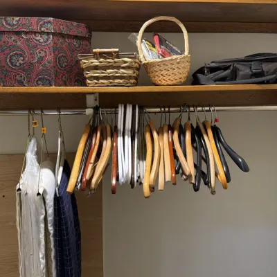 Sale Photo Thumbnail #115: Assorted closet storage items including a paisley fabric-covered box, woven baskets, a black duffel bag, and a collection of wooden, plastic, and wire hangers.