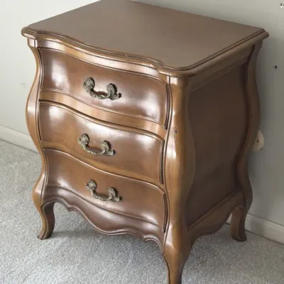 Sale Photo Thumbnail #103: French Provincial style three-drawer nightstand with a serpentine front, curved legs, and ornate brass-finished pulls.