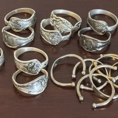 Collection of vintage sterling silver spoon rings and open cuff rings, featuring various ornate floral and scrollwork patterns.