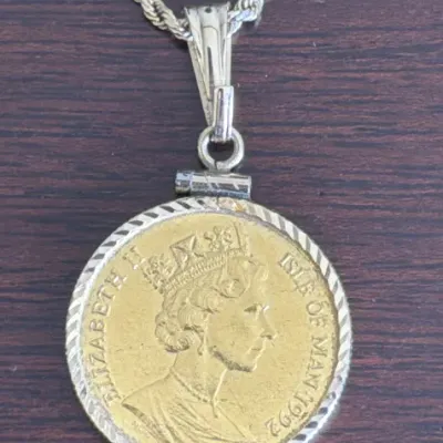 Sale Photo Thumbnail #299: Isle of Man 1992 gold coin pendant featuring Queen Elizabeth II, set in a silver-tone rope-border bezel on a matching rope chain.