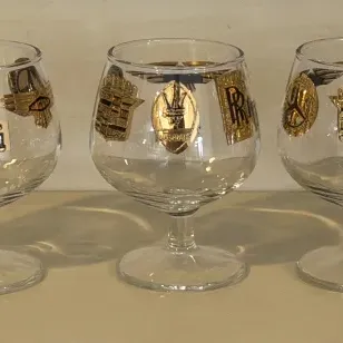 Set of five vintage mid-century brandy snifters featuring gold-embossed luxury automobile logos, including Ferrari, Mercedes-Benz,...