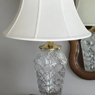 Sale Photo Thumbnail #102: Vintage cut crystal table lamp with brass accents, a footed base, and a white fabric bell shade.