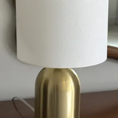 Modern table lamp featuring a brushed brass dome-shaped base and a white drum shade.