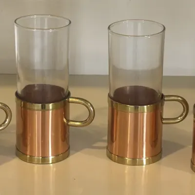 Set of four mid-century modern glass mugs featuring copper sleeves with brass trim and handles.