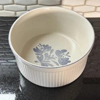 Vintage Pfaltzgraff Yorktowne pattern stoneware soufflé dish, featuring a ribbed white exterior and a blue floral motif on the interior...