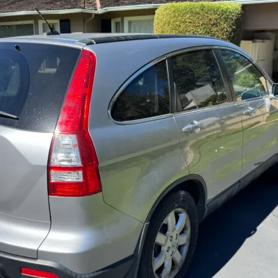 Silver third-generation Honda CR-V SUV, showing the rear and passenger side profile parked in a driveway.