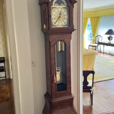 Vintage burl wood grandfather clock featuring an ornate brass dial with a moon phase indicator and a glass-paneled door revealing the...