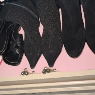 Selection of women's black footwear, including pointed-toe boots with textured detailing, suede boots, and casual sandals.