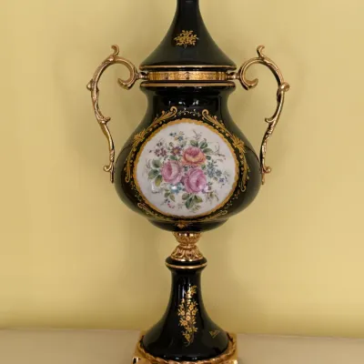 Vintage Italian porcelain lidded urn featuring a black glaze, ornate gold-gilt handles and accents, and a hand-painted floral medallion.