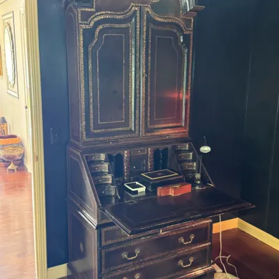 Antique Queen Anne style secretary desk with a bonnet top, featuring gold-painted trim detailing, a drop-front writing surface, and lower...
