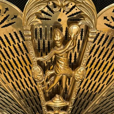 Vintage brass peacock-style fireplace screen featuring an ornate central handle with a dancing female figure motif.