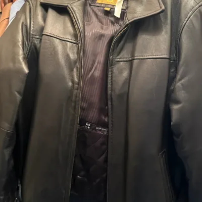 Boston Harbour black leather jacket with a zippered front and quilted lining, hanging in a closet.