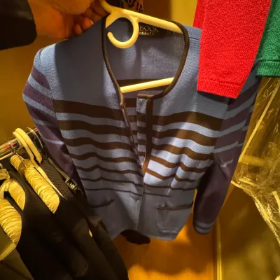 Misook Petite blue and black striped knit jacket with a collarless open-front design, shown hanging in a closet.