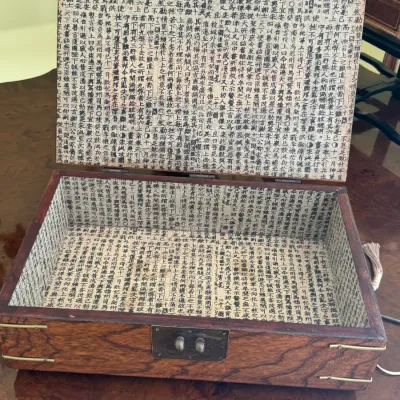 Vintage wooden keepsake box with a metal latch, featuring an interior lined with paper printed with Chinese calligraphy.