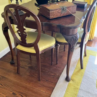 Chippendale-style mahogany game table with cabriole legs and shell carvings, paired with matching shield-back chairs featuring yellow...