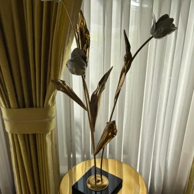 Vintage brass and ceramic tulip sculpture on a black laminate base, displayed on a polished brass side table.