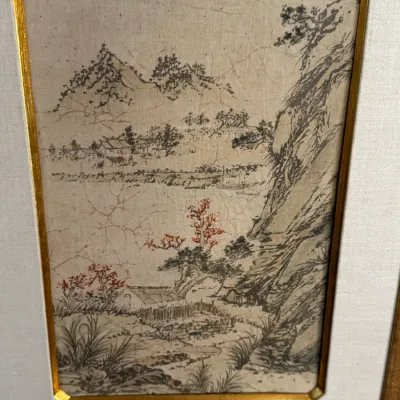 Framed East Asian landscape painting on silk or paper, featuring a mountainous river scene with small dwellings and red-blossomed trees,...