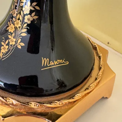 Close-up of a Maroni black ceramic lamp base featuring gold floral details, a gold-painted signature, and a metallic gold-toned pedestal...