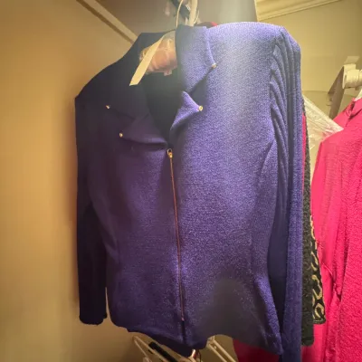 Vintage St. John purple knit zip-up jacket with structured shoulders and gold-tone hardware, hanging in a closet.
