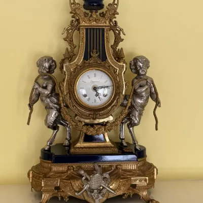 Imperial Italian brass and cobalt blue porcelain mantel clock, featuring two silver-toned cherub figures holding ropes on either side of...
