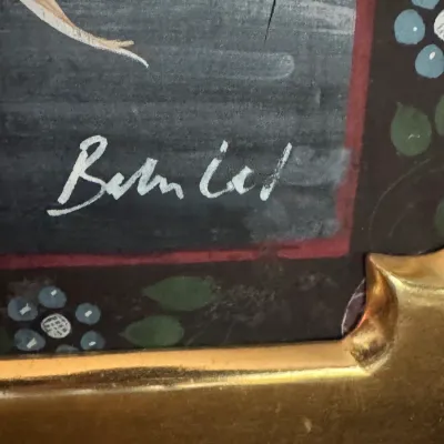 Close-up detail of an artist's signature, reading "Berniel," on a folk art painting with a decorative floral border and a...