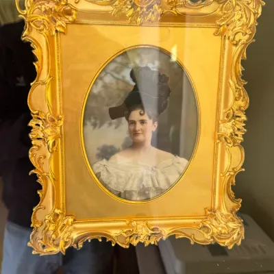 Antique hand-colored portrait of a Victorian woman wearing an elaborate hat, housed in an ornate, gilded Rococo-style frame.
